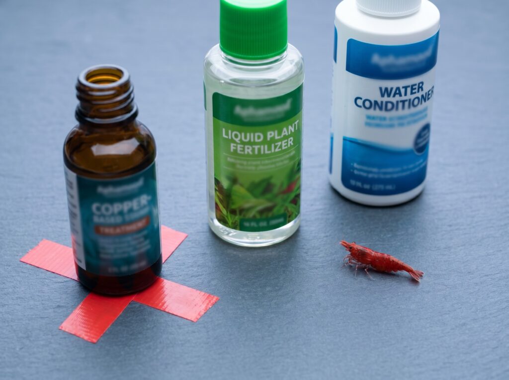 copper-based fish medication next to plant fertilizer with a caution marker near shrimp